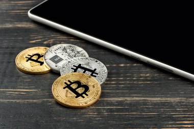Ahşap arka plan üzerinde bir tablet ile altın ve gümüş sikke bitcoin