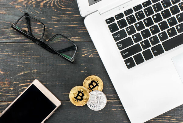 Bitcoin coins with a laptop, a mattress and glasses on the table, top view