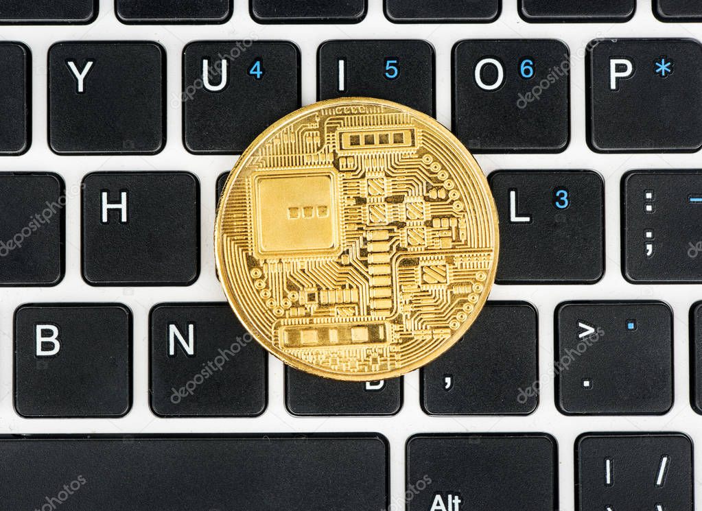 Back side of bitcoin gold coin on laptop keyboard top view