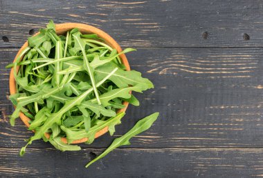 Boş bir ahşap zemin üzerine bir kase taze roka