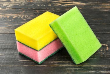 Ahşap arka plan üzerinde bulaşık için üç renkli süngerler