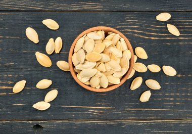 Ahşap arka plan, üstten görünüm üzerinde kabuğundaki kabak çekirdeği ile küçük kase