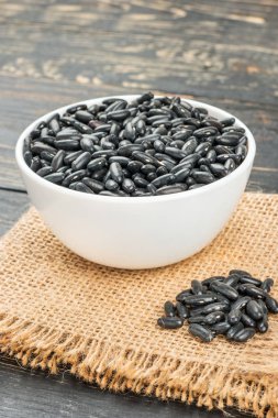 Bir kase siyah fasulye çuval bezi portre üzerinde dağınık.