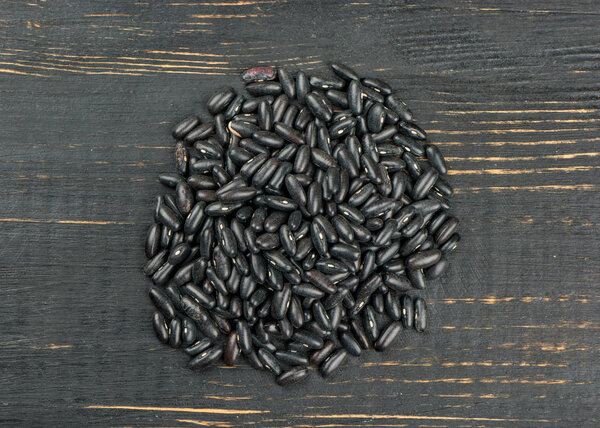 Pile of raw black beans on wooden background, top view