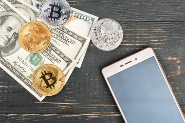 Altın ve gümüş bitcoin paralar ile dolar ve ahşap arka plan üstünde smartphone