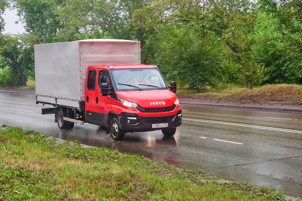Krasnoyarsk, Rusya - 30 Temmuz 2018: bir yağmur ıslak yolda geçen Iveco Daily kırmızı renk .