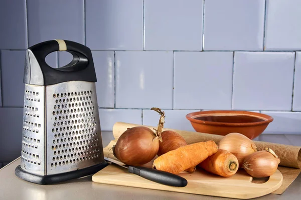 vintage kitchen utensils, grater, carrots, onions, against the background of an old vintage tile