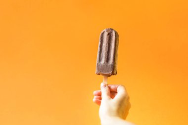 Parlak turuncu zemin üzerine çikolatalı dondurma.