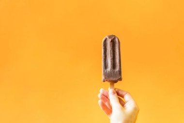 Kızın elini tutarak çikolata dondurma parlak turuncu zemin üzerine.