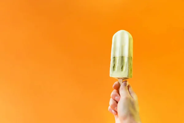 Girl Hand Bedrijf Groene Ijs Een Helder Oranje Achtergrond — Stockfoto