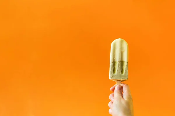 Groene Ijs Een Meisje Hand Een Helder Oranje Achtergrond — Stockfoto