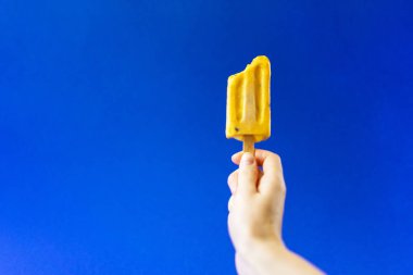 Derin mavi bir arka plan üzerinde sulu sarı dondurma.