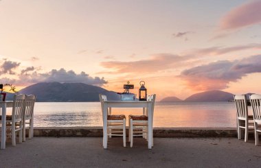 Tablo iki şişe şarap, işareti ayrılmış, mum aydınlatma ve arka plan üzerinde harika gün batımı ile seafront görev yaptı.