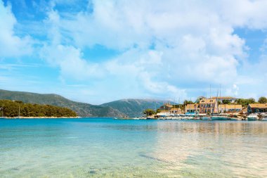 Grecian köyü Fiscardo, turkuaz deniz ve bulutlu gökyüzü yukarıdaki Kefalonia Bright evler.