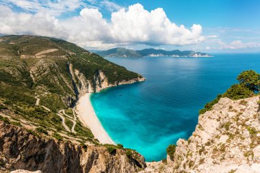 Myrtos Kefalonia Adası'nda güneşli gün sahilde. Yılan gibi yolda bir yeşil tepe ve turkuaz İyon Denizi.  