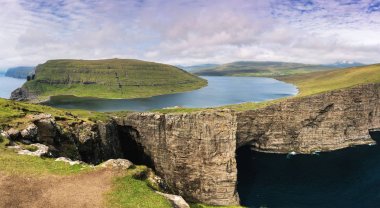 Vagar Adası 'nın en güzel dönüm noktası-Leitisvatn Gölü. Okyanus ve kayalıkların üzerinde göl ile inanılmaz Panorama. Faroe Adaları.