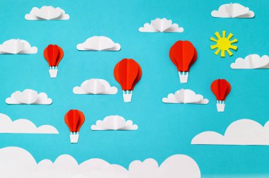 Kağıt kesilmiş ve origami sıcak hava balonları, bulutlar ve güneş. Afiş/iniş/arka plan tasarımları için yaratıcı konsept.