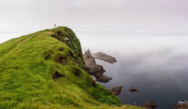 Deniz feneri ve okyanus üzerinde kayalıklar ile Mykines adanın panoramik manzara. Faroe Adaları.