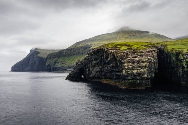 Okyanus kıyısındaki ada kayalıkları. Faroe Adaları 'nın atmosferik manzarası.