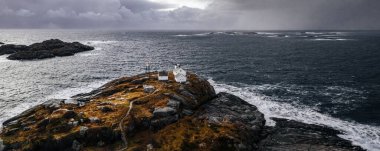 Adanın kıyısındaki küçük ev ve ufuktaki fırtınalı deniz. Lofoten Adaları natürmort fotoğrafı.