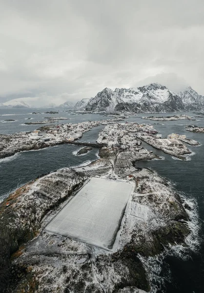 Henningsvr soccer field at winter covered with snow with outstanding mountain on horizon. Lofoten Islands, Norway.