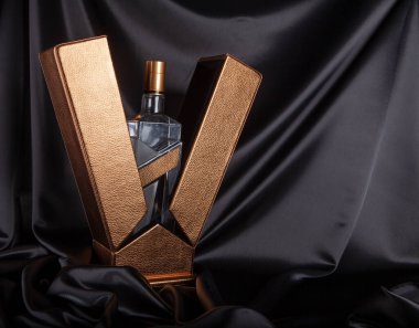 Siyah arka planda, altın bir kutuda şişe, alışılmadık bir açı.