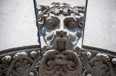 Binanın ön cephesinde Barillef, ürkütücü taş bir yüz ve çiçek deseni, mimaride antik Roma motifleri. Evin girişinin üstündeki dekorasyon..