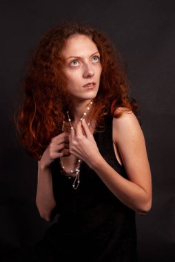 Güzel kızıl saçlı, açık tenli, kıvırcık saçlı, portresi olan bir kadın.