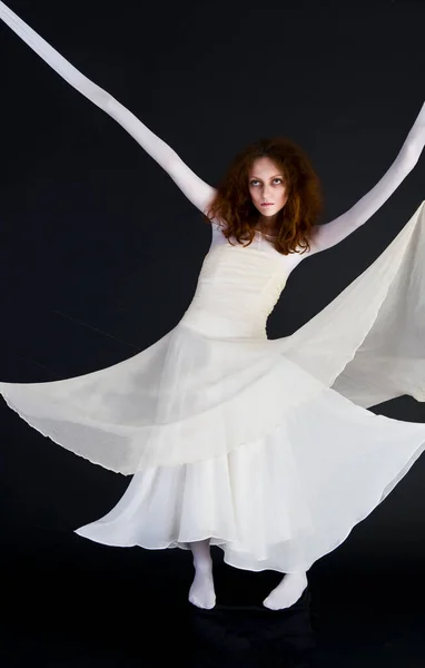 An image for halloween, a red-haired woman in the image of a witch in a white outfit with a pale deathly face