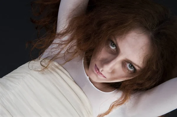An image for halloween, a red-haired woman in the image of a witch in a white outfit with a pale deathly face