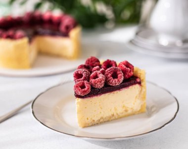 Ahududulu cheesecake. Ahududu ve ahududulu reçelli cheesecake. Beyaz tabakta bir dilim cheesecake. Çay zamanı.