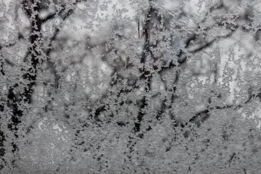 Pencereye su damlatan buz penceresi kar ve kar taneleri ve arka plandaki buz kristalleriyle birlikte kış penceresi camları düşürür.