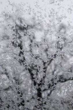 Kış buz dokusu, donmuş su, kar ve kar taneleri olan pencere camları pencereye buz kristalleri bırakıyor.