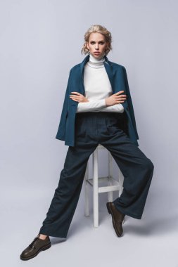 Sarışın, güzel saçlı, mavi takım elbiseli güzel bir kadının moda fotoğrafı. Klasik ceket giymiş zarif bir genç kızın portresi. Stüdyo fotoğrafı. Şık bir kadın..
