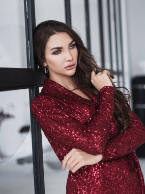 Modayı takip eden kırmızı takım elbiseli zarif bir kadın. İzole edilmiş bir stüdyo fotoğrafı. Moda ve tarz. Güzellik ve Sağlık. Vogue. Stüdyoda moda tarzında poz veren bir kız. Moda tonu ve poz verme. Havalı görünüm.