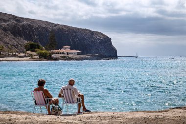 Los Cristianos, Tenerife, İspanya - 18 Şubat 2019: Yaşlı çift tatilde, Atlantik Okyanusu kıyısında, Kanarya Adası 'nın popüler tatil beldelerinden birinde dinleniyor..