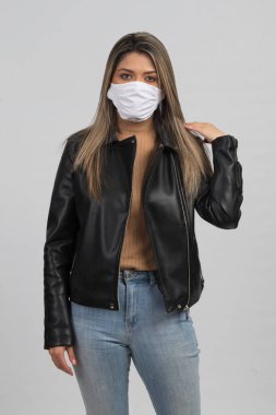  Latin bir kadın morina balığından nasıl korunacağını gösteriyor. Günlük kıyafetler ve beyaz bir maske takıyor. 
