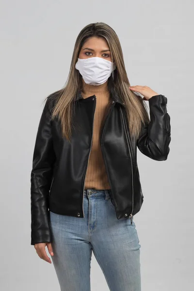  Latin bir kadın morina balığından nasıl korunacağını gösteriyor. Günlük kıyafetler ve beyaz bir maske takıyor. 