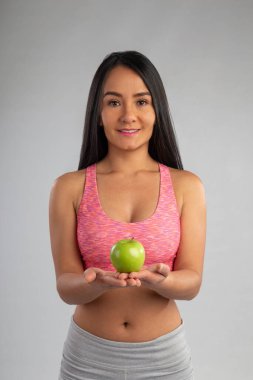 Güzel Latin kadın gülümsüyor ve ellerinde organik sulu yeşil bir elma tutuyor.. 