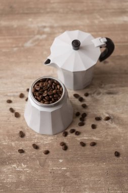 Kahve çekirdekli kahve demliği ahşap bir masada.