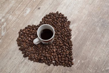 Kahve çekirdekli, kalp şeklinde bir fincanın üst görüntüsü.
