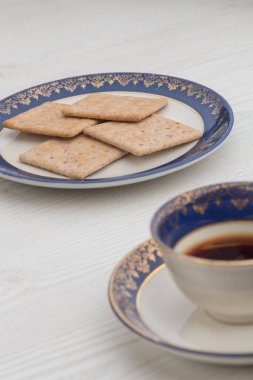 Kurabiyeli porselen tabak ve çok zarif beyaz tahta bir yüzey üzerinde bir fincan çay.