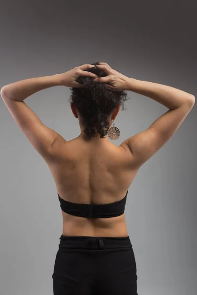 toned back of a woman with curly hair on a gray background