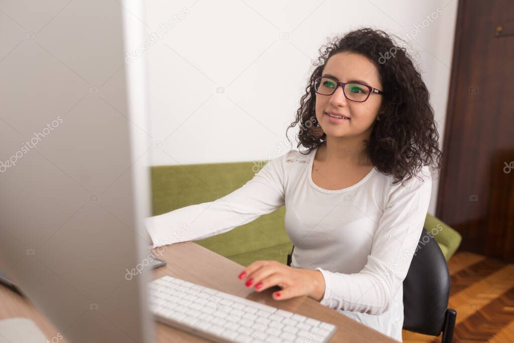 latin woman with curly hair working in an office with a computer