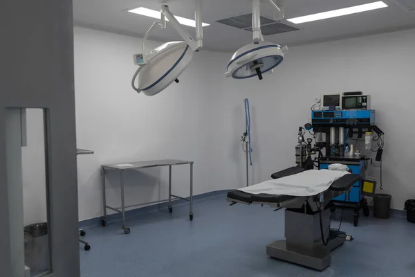 white medical center room, with a stretcher, lamps, tables and medical instruments