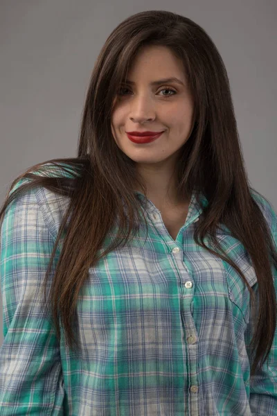 face of young woman with white skin, light eyes, long hair and red lips, wearing plaid shirt, studio shot
