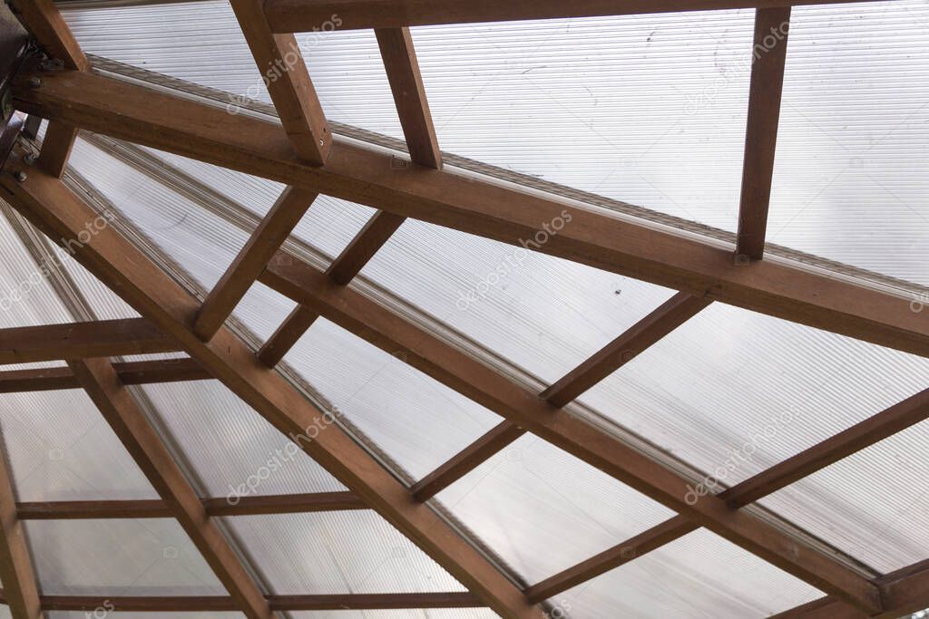closeup to a ceiling with joining wooden beams and transparent polycarbonate