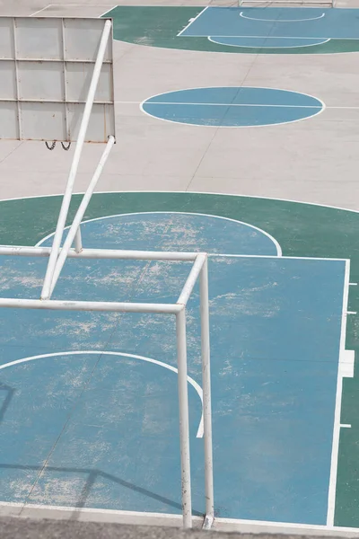close-up of a cement basketball and soccer court, painted in different colors alone, photo with daylight
