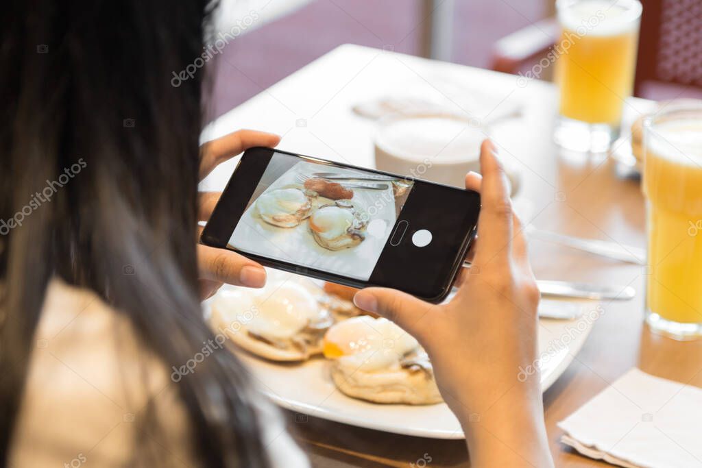 person taking a photo with cell phone at breakfast, photo in the day