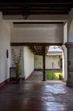 Geleneksel Ekvador hacienda koridoru ahşap kirişler, taş detaylar ve küçük bir avlu manzarası, kırsal sömürge cazibesini yansıtıyor..